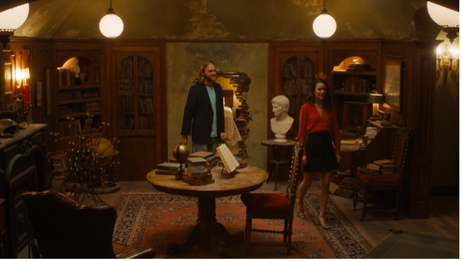Dud and Emily talking in the lodge library.
