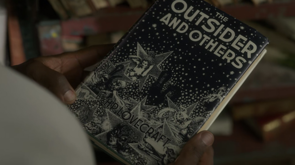A close-up shot of a pair of hands holding a first-edition copy of H.P. Lovecraft's The Outsider and Others.