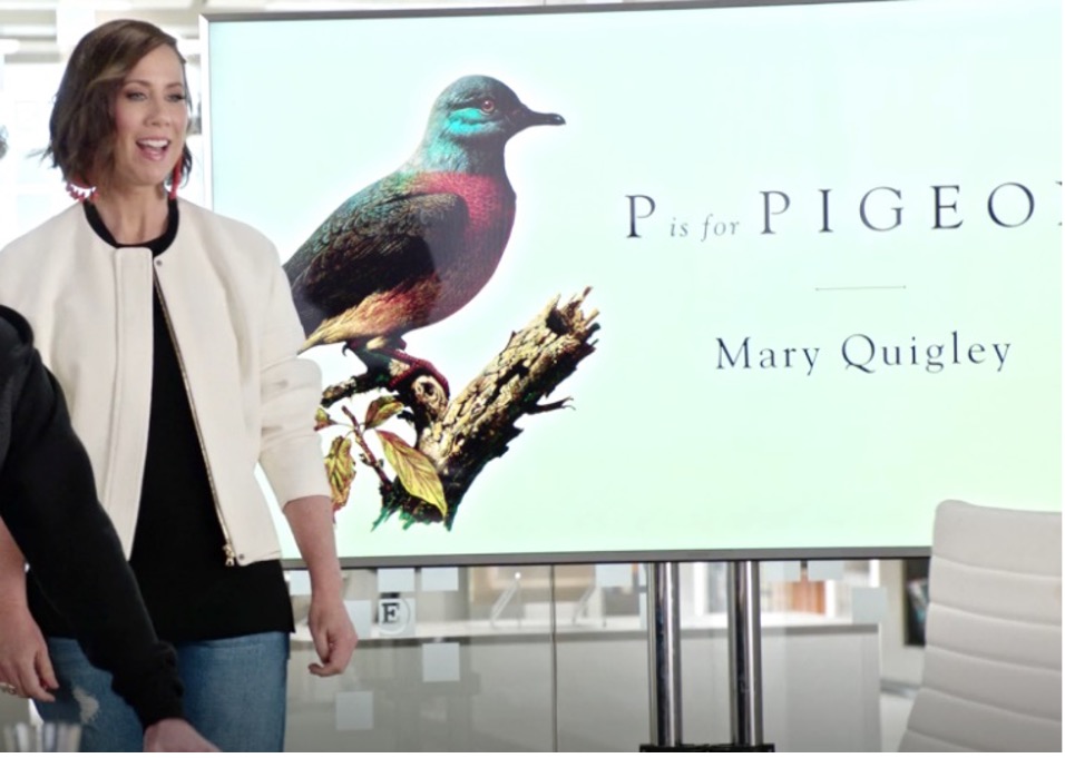 Diana, a marketing executive, brunette with a power bob, stands in front of a presentation. The first slide shows a multi-coloured bird on a branch and reads